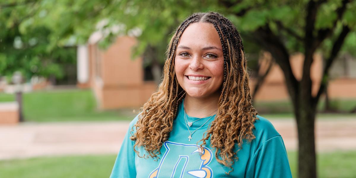 Nadia Suber outside and smiling. She is wearing an AACC Volleyball t-shirt.