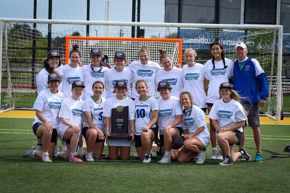 AACC's women's lacrosse team posing with the trophy on the field.