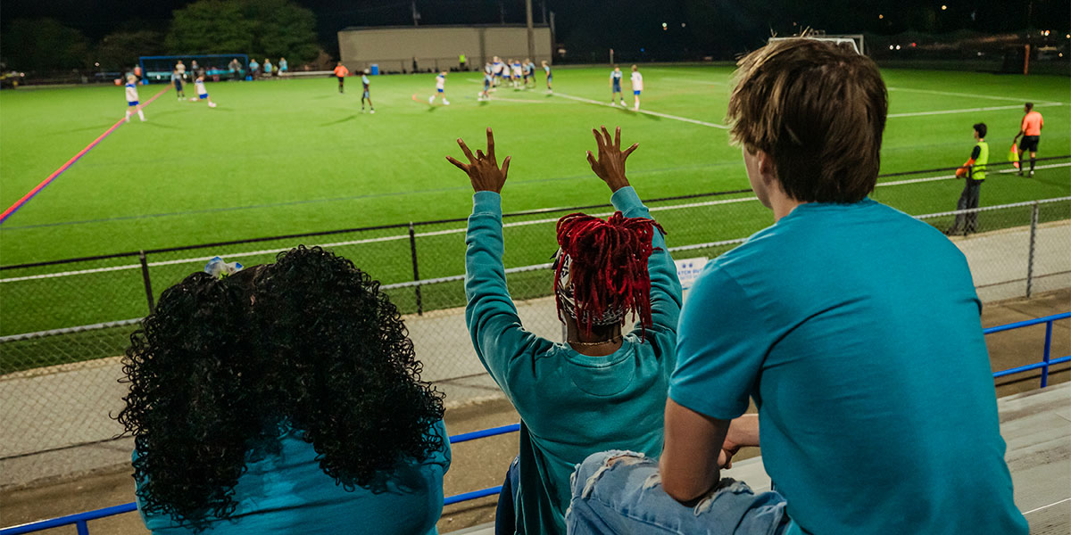 Students cheer on athletes at a soccer game