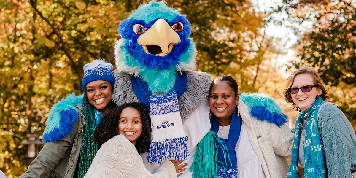 Students with Swoop the Riverhawk on campus in fall