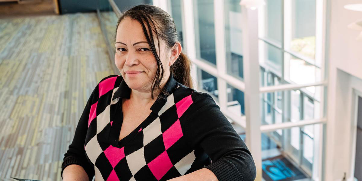 A woman wearing a black, white and pink sweater smiles at the camera.