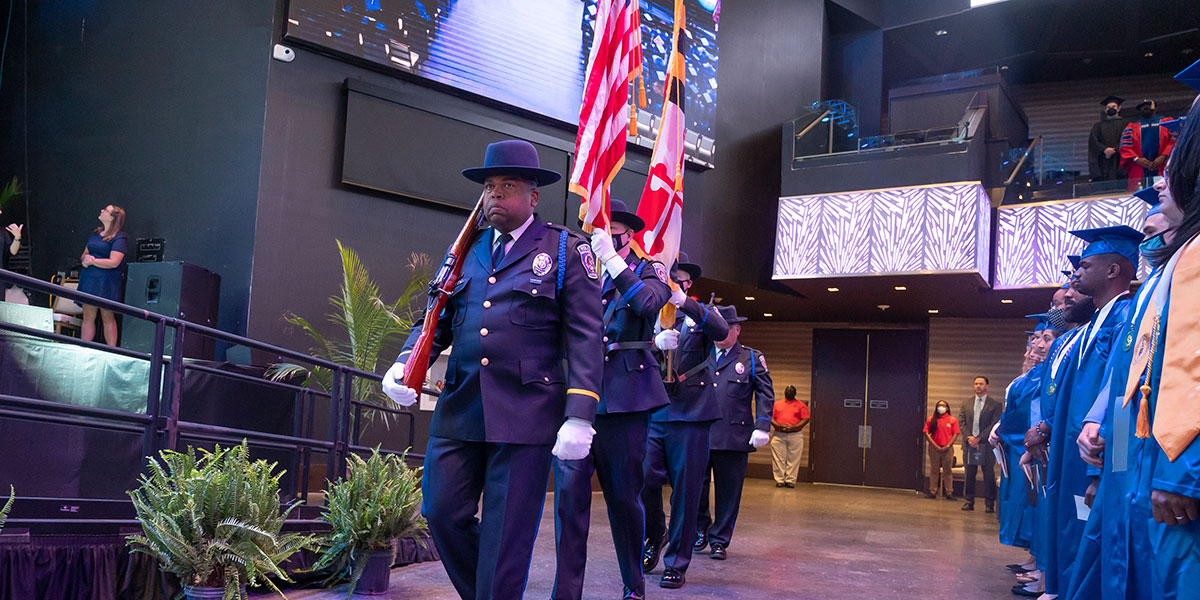 Department of Public Safety & Police officers in uniform and carrying flags at graduation