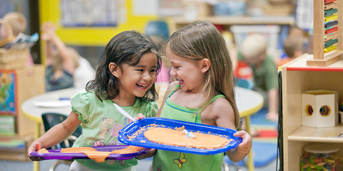Two girls giggle together in AACC's Child Development Center.