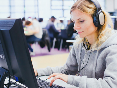 woman at computer with headphones