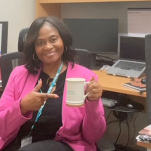 Stephanie Smith-Baker holding and pointing to coffee mug in office