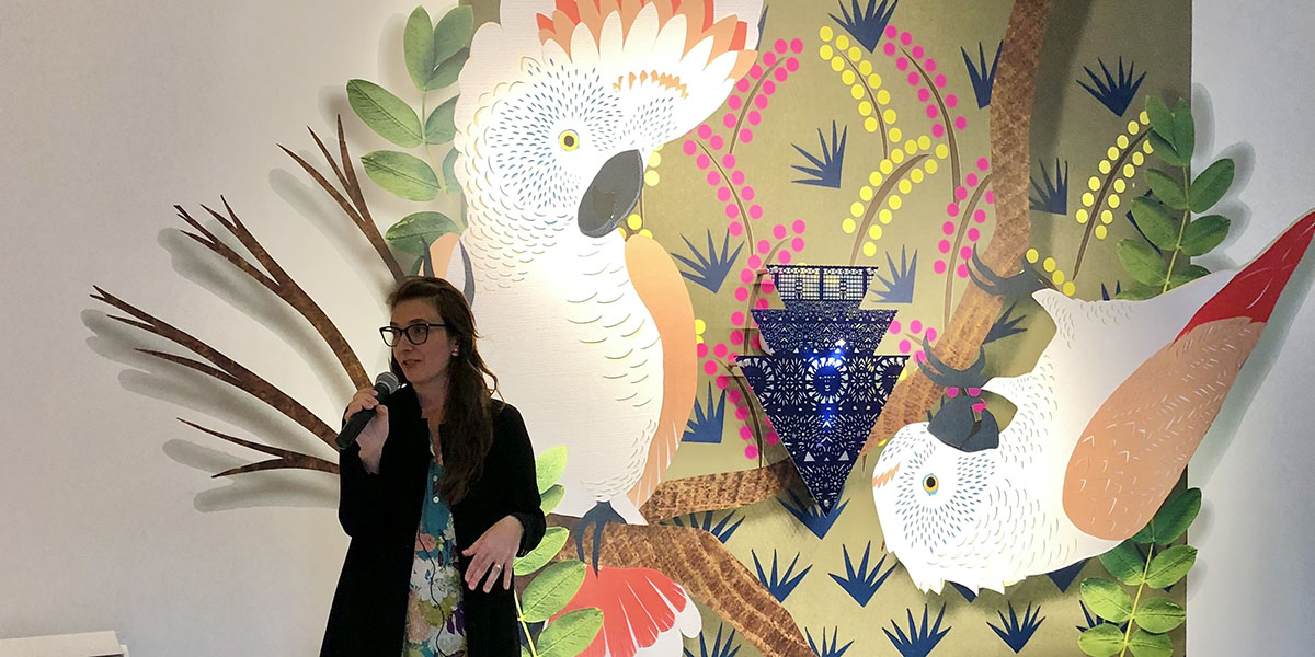 Zoe Friedman standing in front of artwork featuring birds