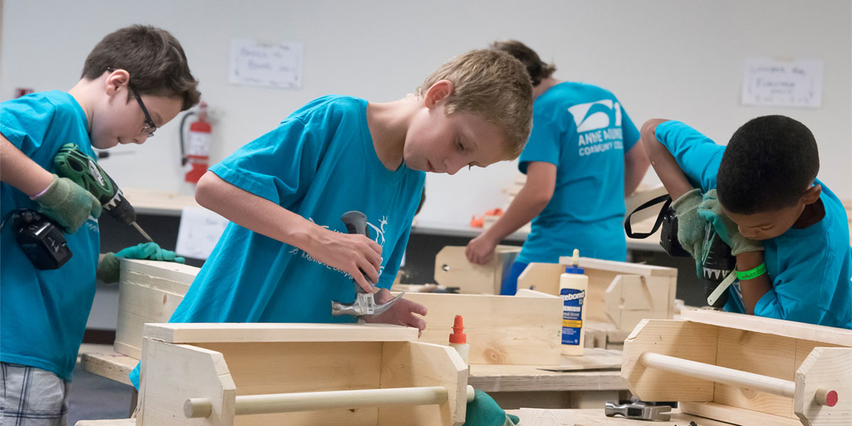 Kids in college building with woodworking tools.