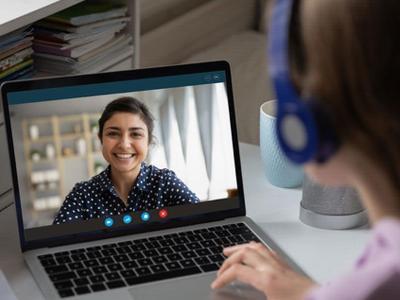 Person with headset viewing a video call on laptop.