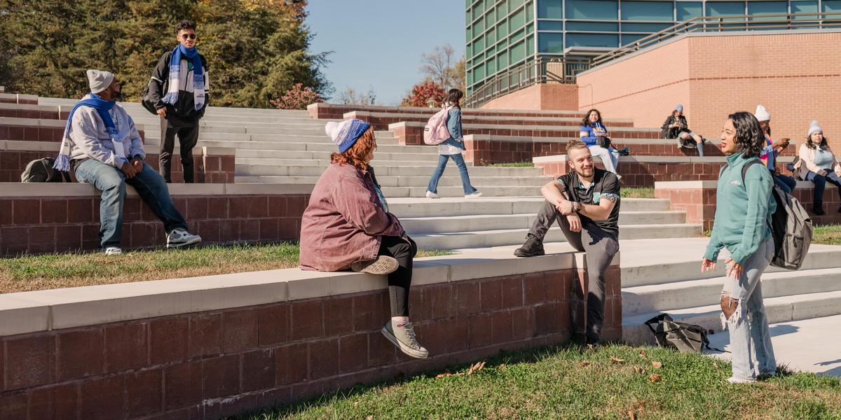 Group of students talking to one another outside in amphitheater.