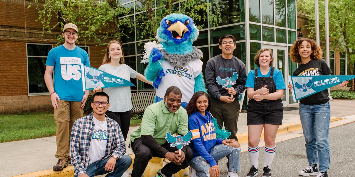 Group of AACC students wearing AACC gear and posing with Swoop.