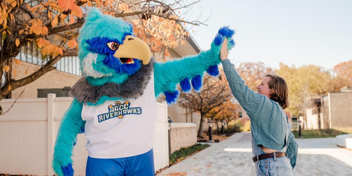 Student high-fiving AACC mascot, Swoop.