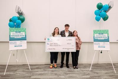 Nehemiah Robison holding a giant check with Hannah Gribbin and Stephanie Goldenberg.
