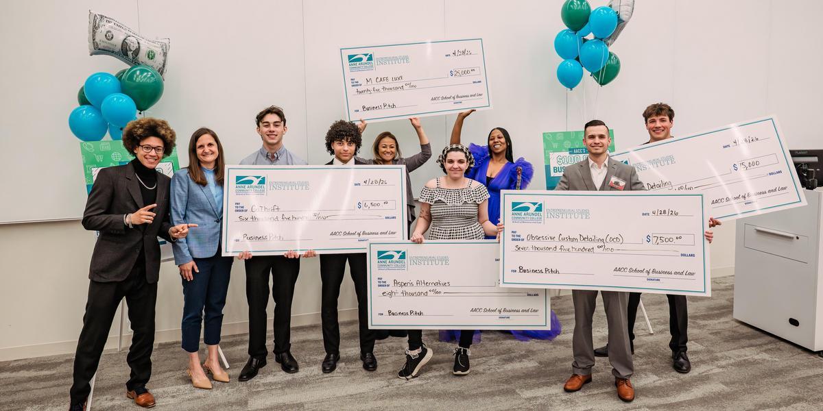 Group of business pitch winners posing with oversized checks.