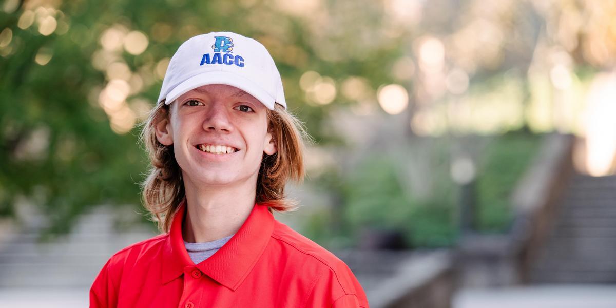 Nicholas's formal headshot. He is wearing a red ambassador shirt and an AACC ballcap.