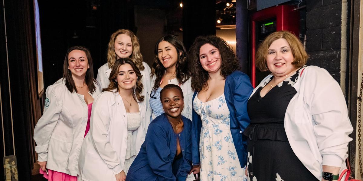 A group of medical assisting graduates pose together and smile.