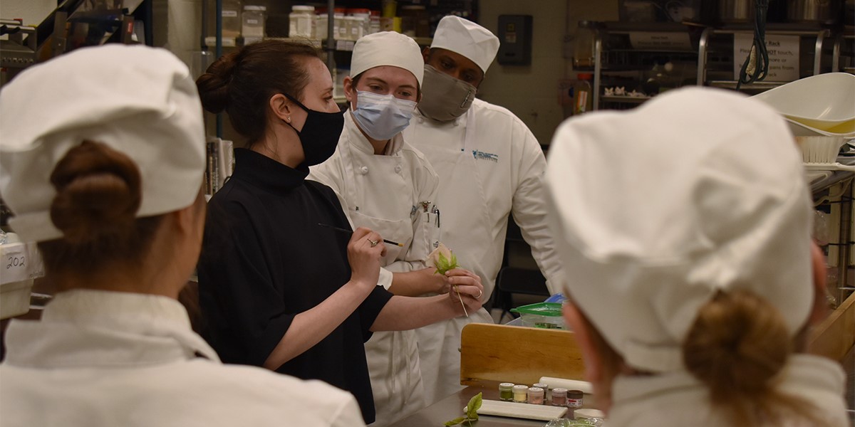 Maggie Austin demonstrating a gum paste rose to a room full of culinary students at AACC.