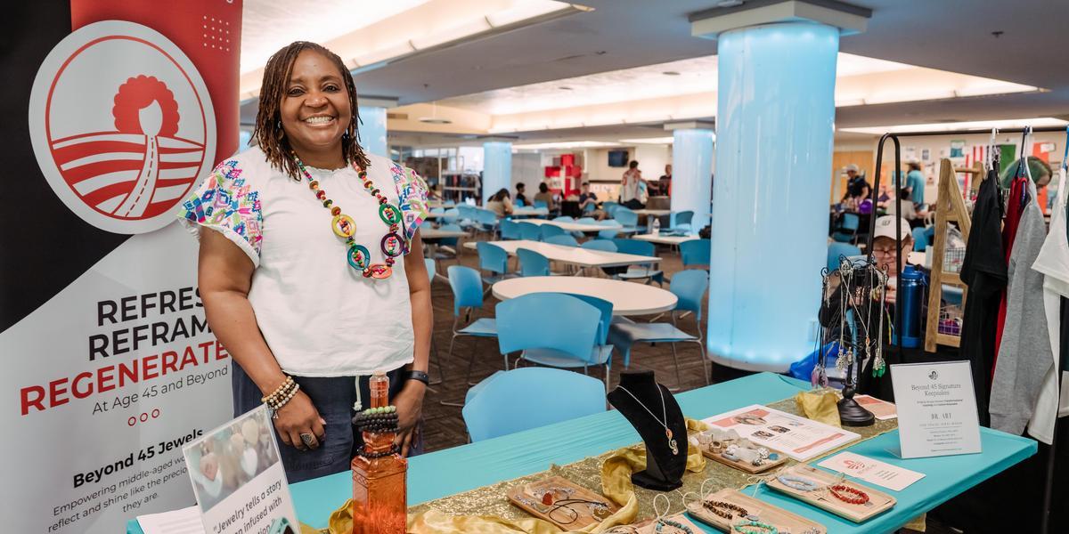 Artensie Flowers stands behind a table cover with jewelry during the student trade show event.