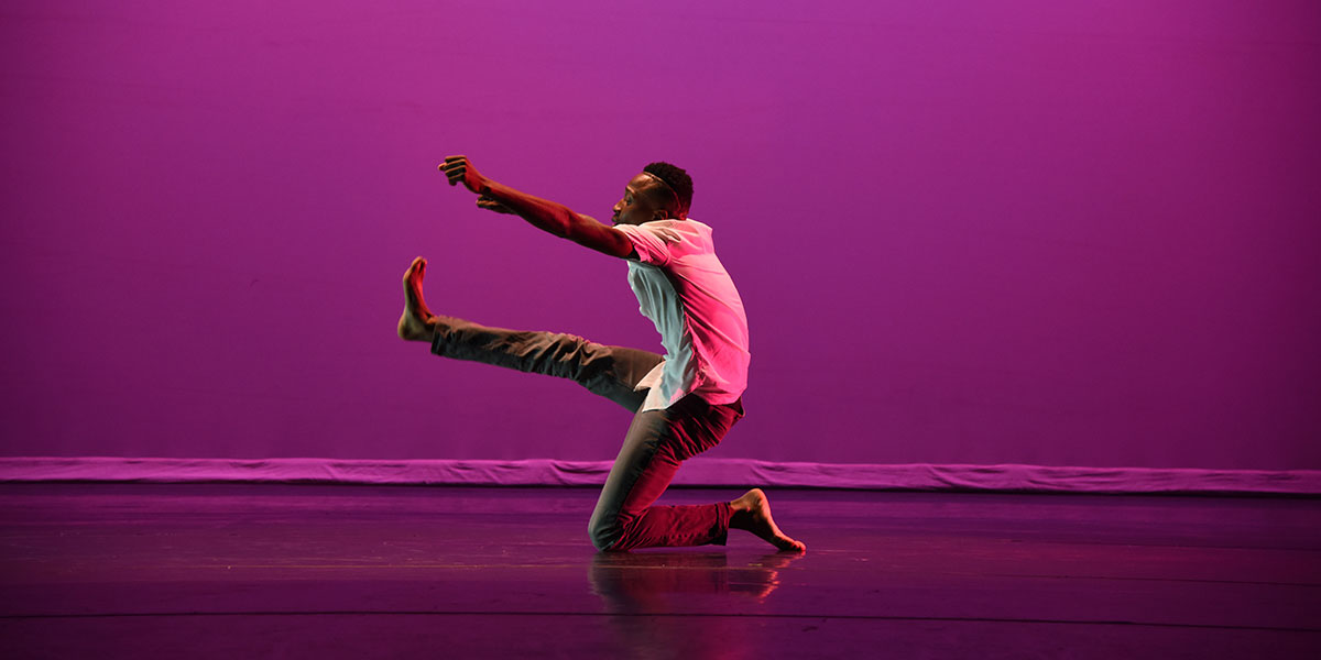 Man dances on purple stage.