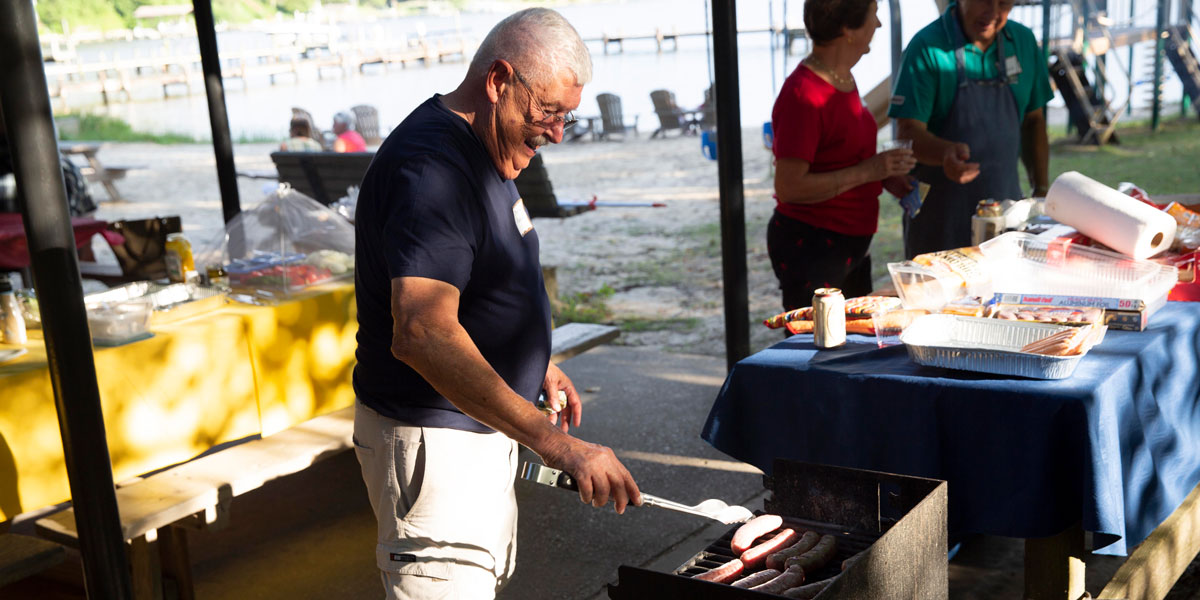 Man outside cooking food on a grill.