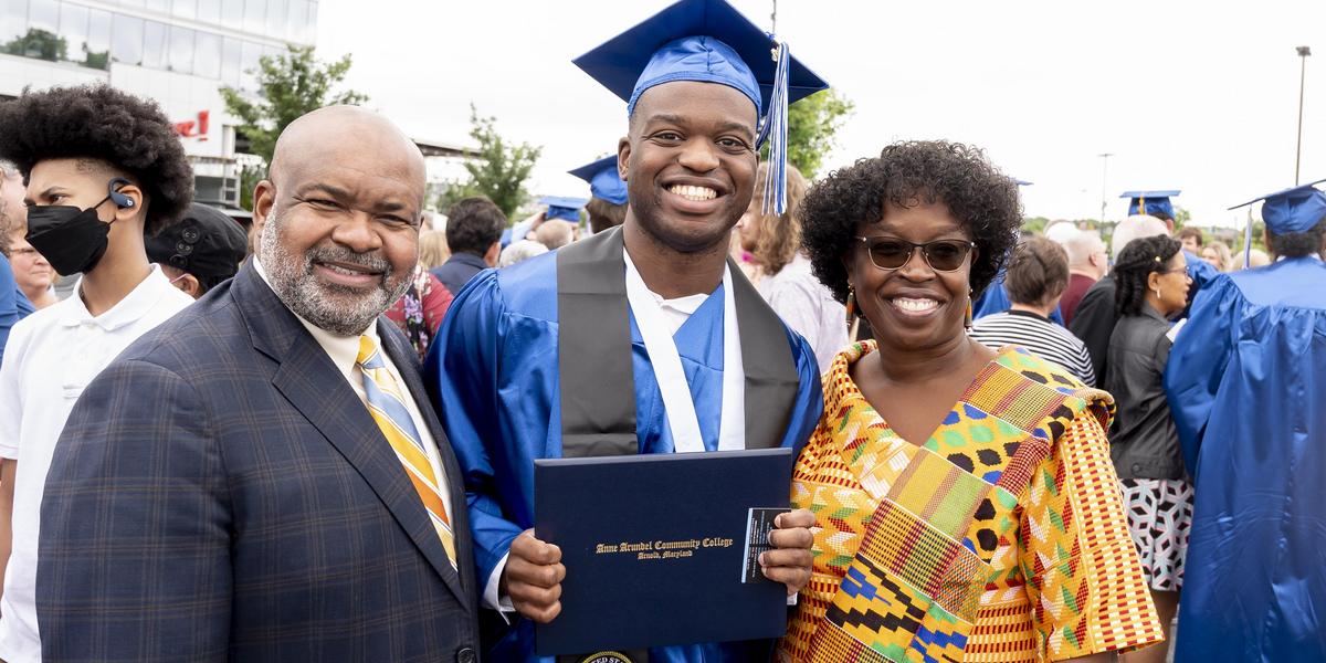 AACC graduate posing with his diploma and family