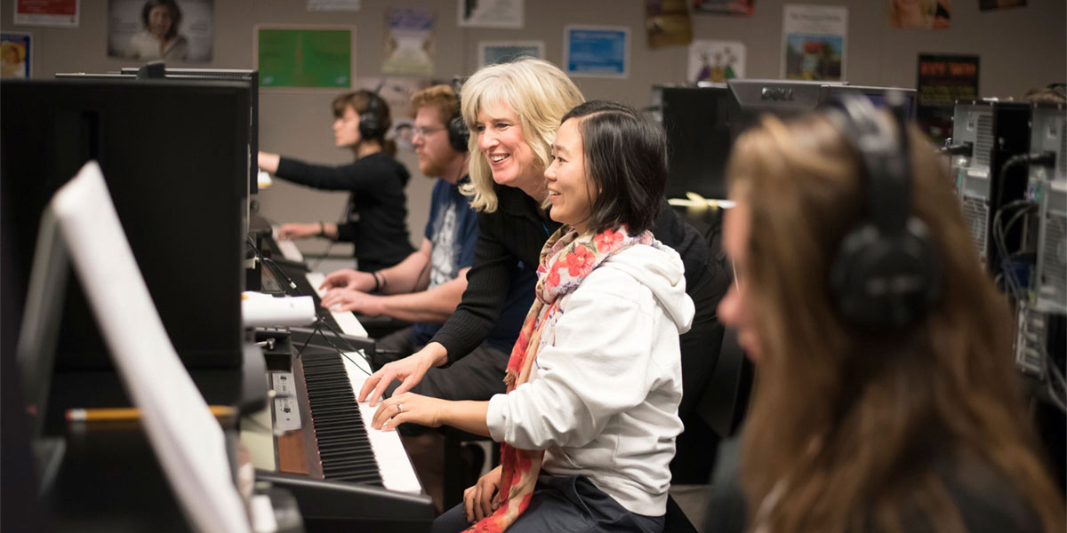 AACC students learn to play piano with the help of instructor.