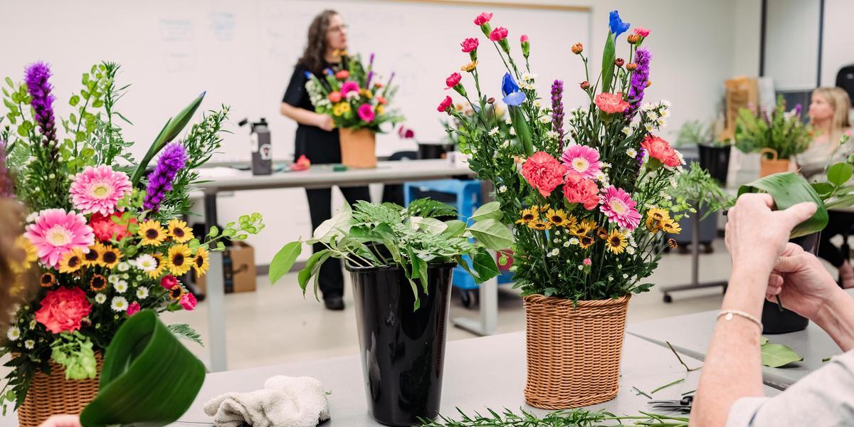 Two students work on bouquets as a teacher speaks.