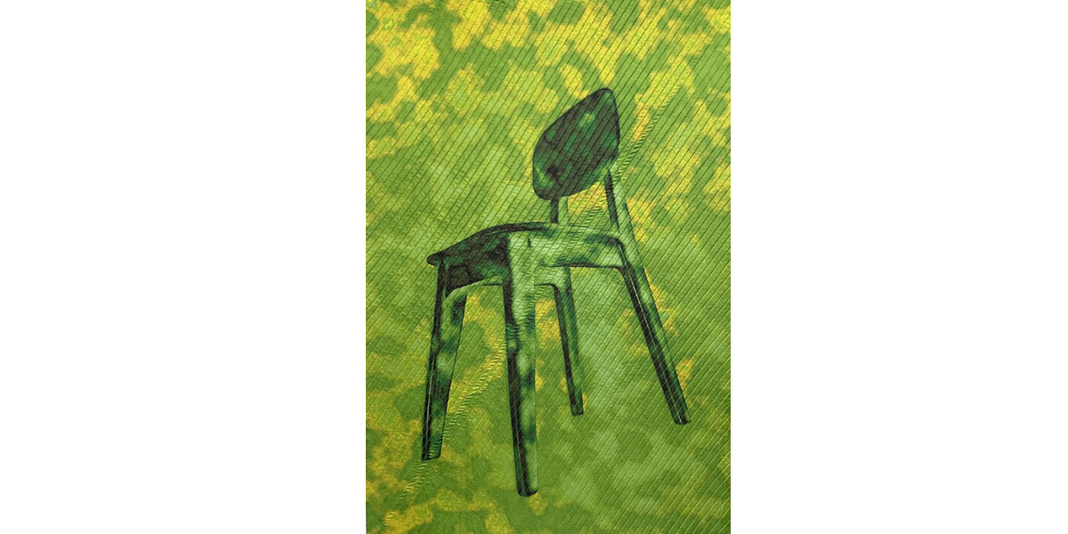 A green and yellow quilted textile artwork depicting a stylized modern chair, with diagonal stitching throughout.