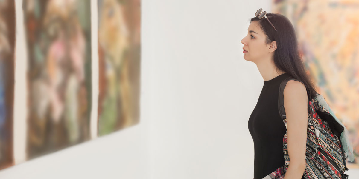 Female student views a painting in an art gallery.