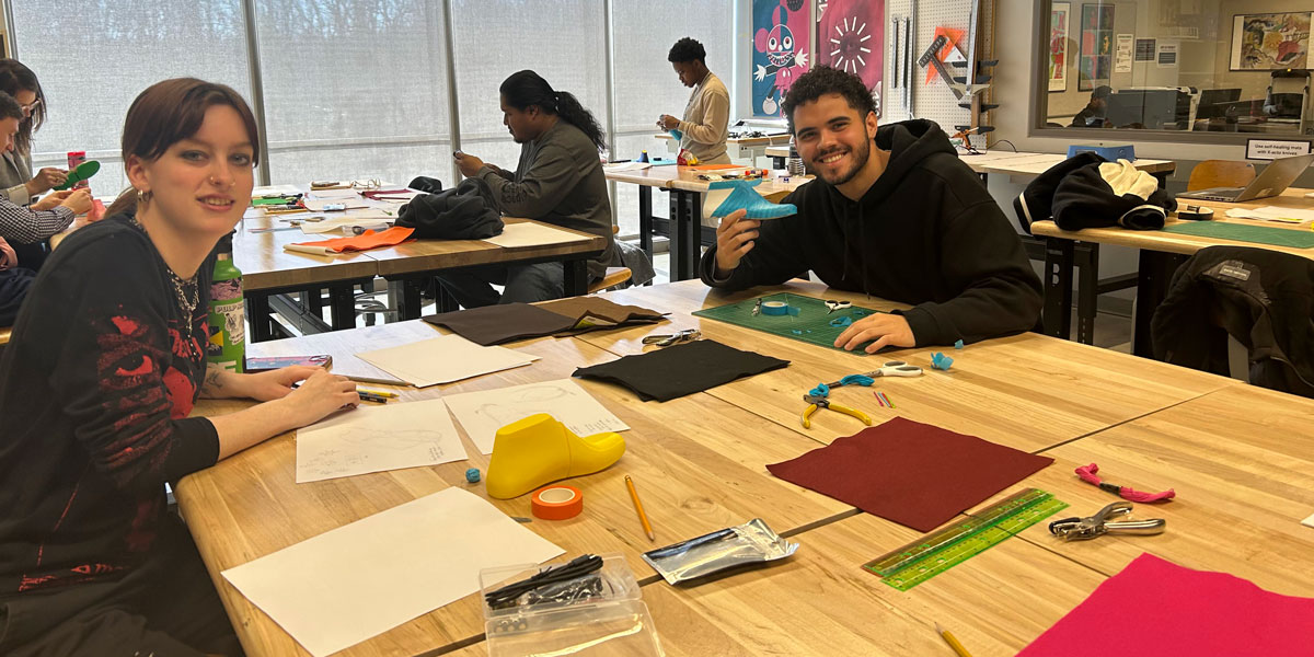 Students working on shoe design project, smiling for photo.