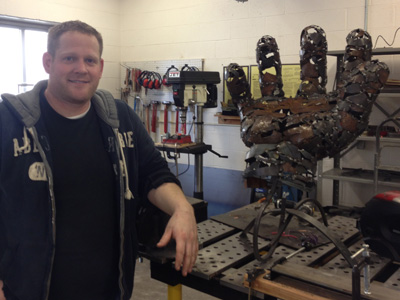 AACC student stands beside his metal sculpture.