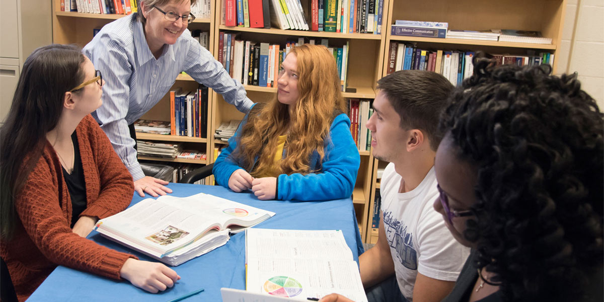 Professor checking in with students studying.