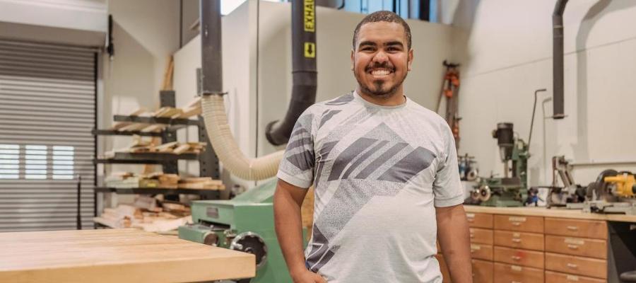 A carpentry student stands in a skilled trades classroom