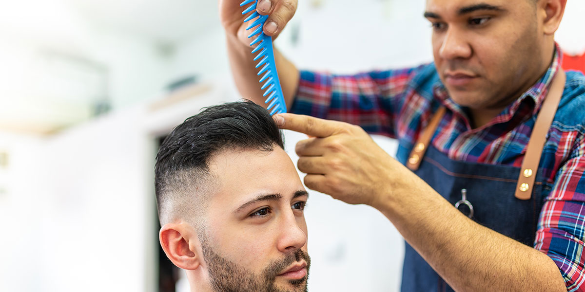 A barber combs a mans hair.