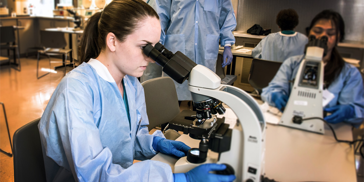 AACC student with microscope in lab