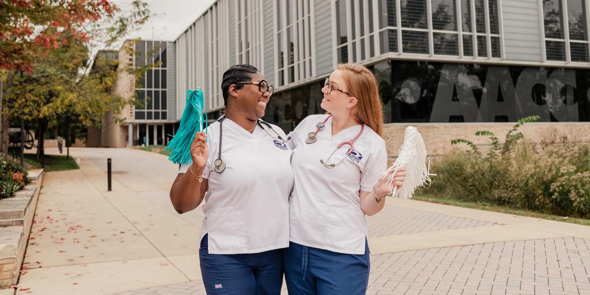 AACC students wearing scrubs and posing outside Library.