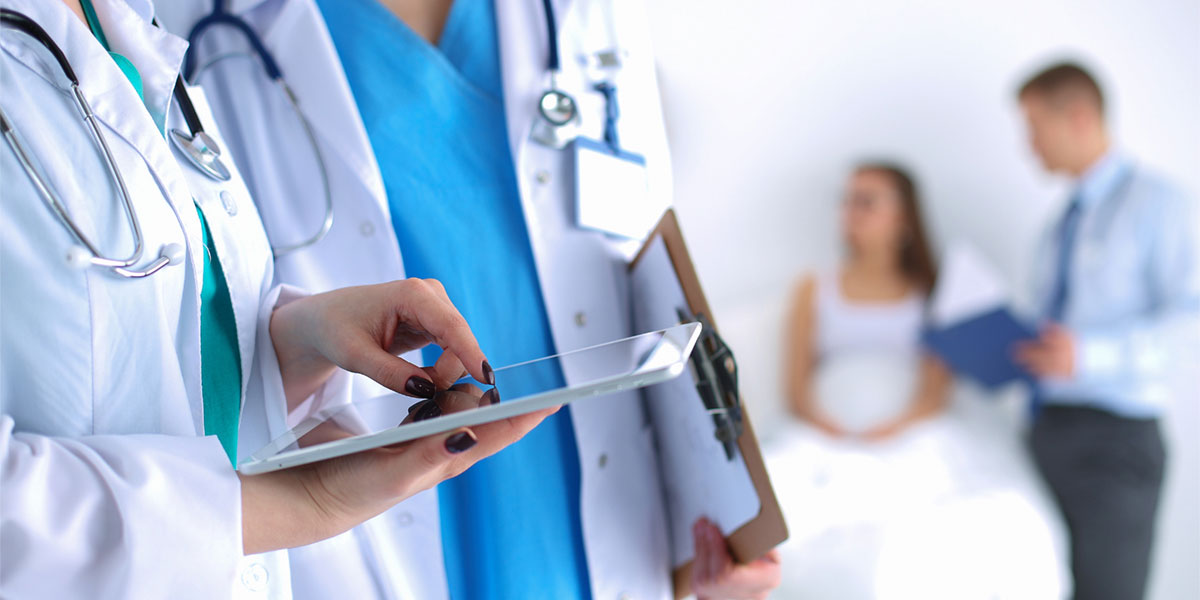 Health care professionals review patient chart on a tablet.