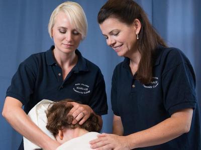 An AACC student gives a patient a massage with the help of her instructor.