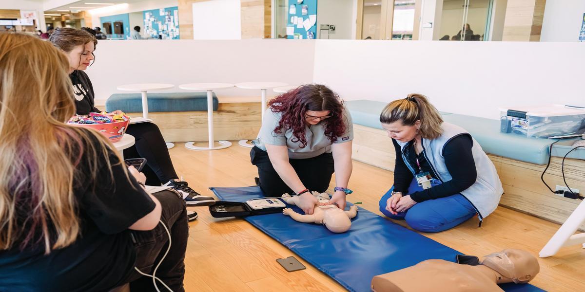 Instructor showing a person how to perform CPR on a baby mannequin