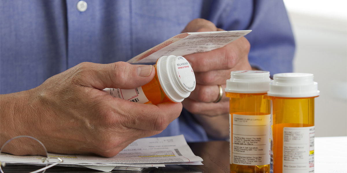 Health care professional with prescription and bottles.