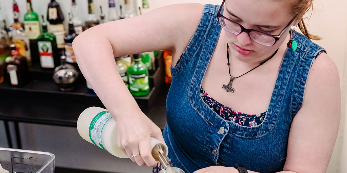 A student pours a drink in a bartending class