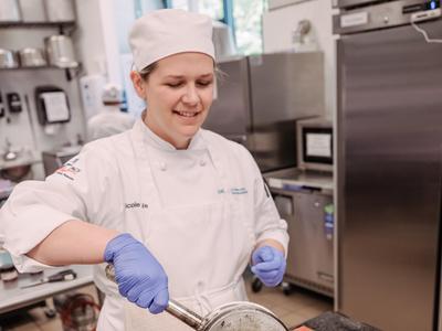 A student wearing a chef outfit working in a Pastillage class.