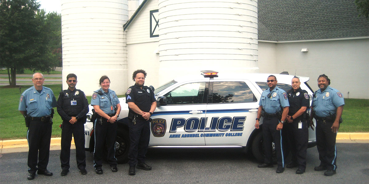 Members of the Department of Public Safety stand next to a police vehicle on campus.