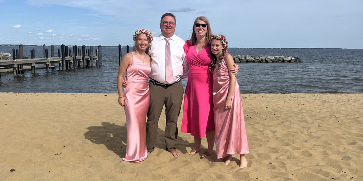 Jennie Hager standing on a beach with her husband and two daughters