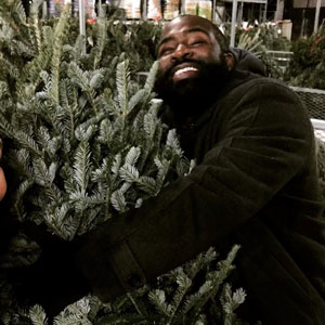 Marcus Wright hugging a Christmas tree.
