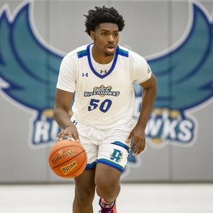 Male basketball player with Riverhawk logo behind him