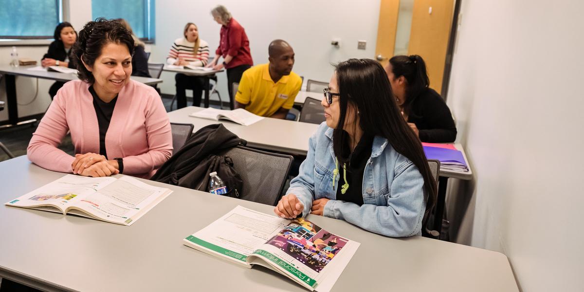 Students in an Anne Arundel Community College class talking with textbooks open in front of them.