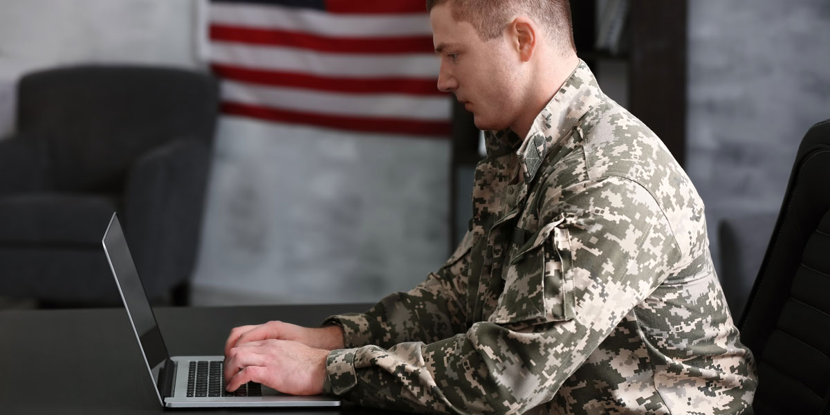 Military man in uniform on laptop inside a resource center.