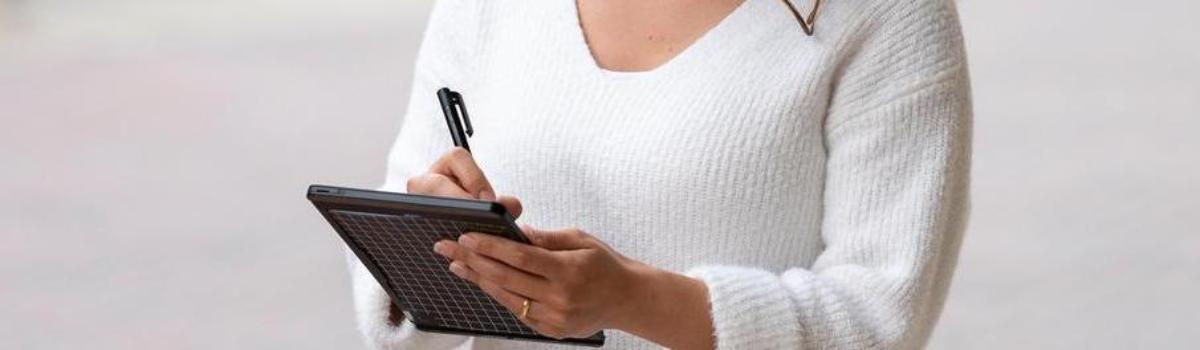 Student outside writing on tablet