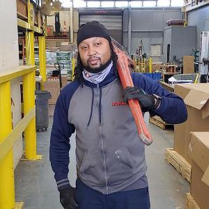 Teddy Strong standing in a warehouse with a piece of equipment over his shoulder.