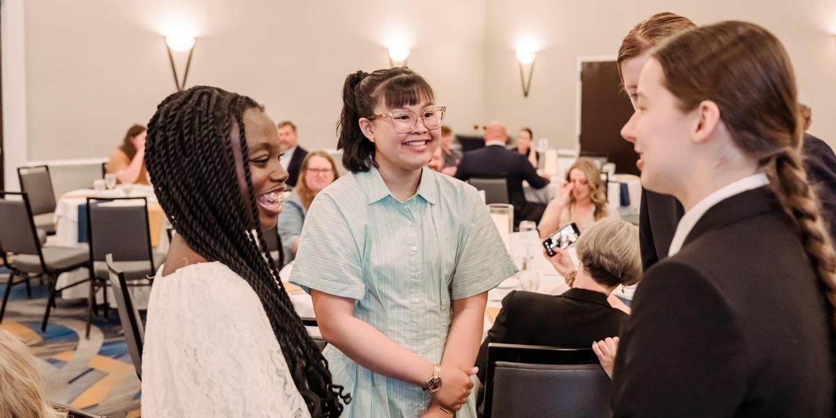 Students in professional attire talking to one another.